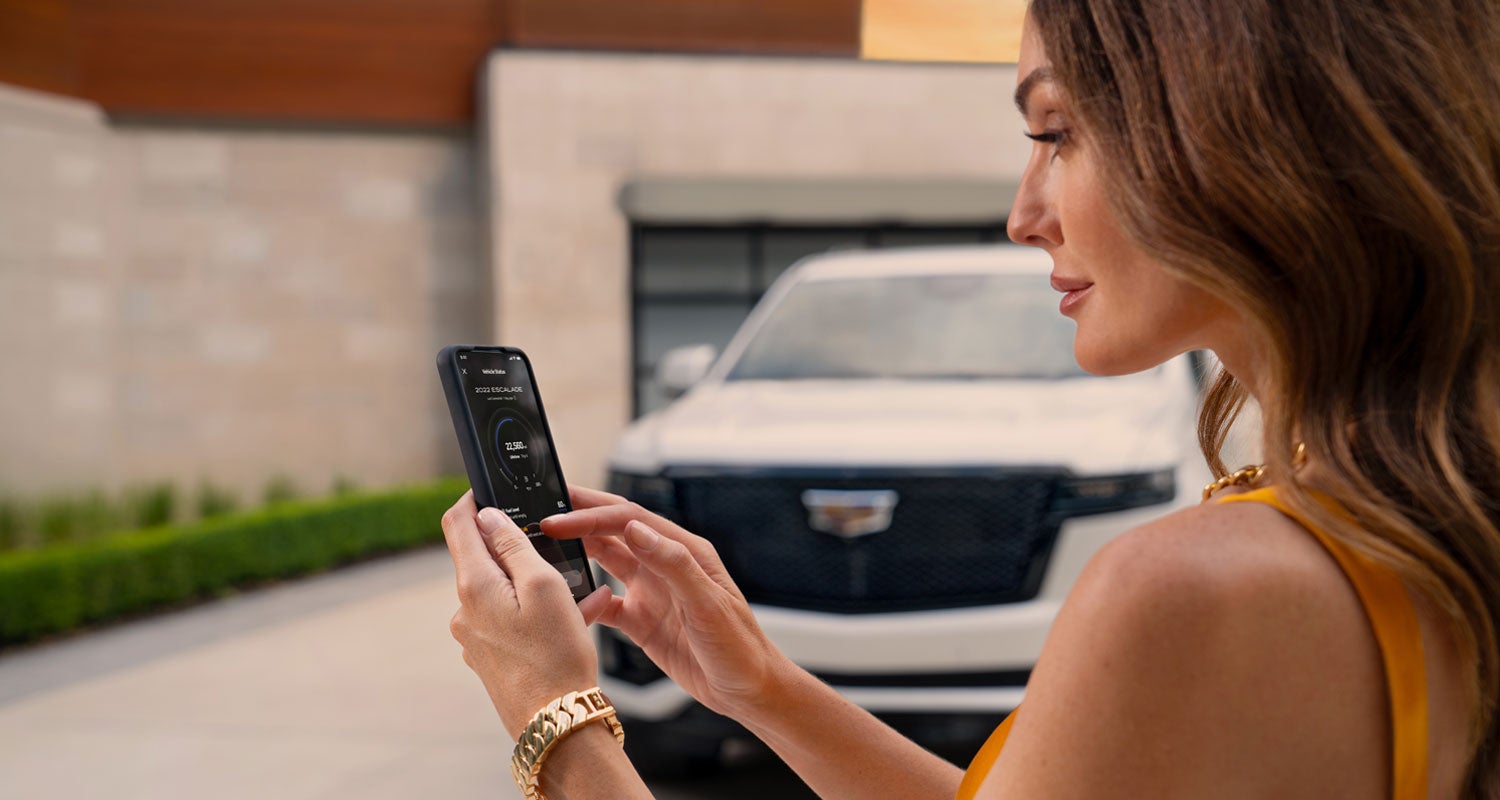 lady checking her mobile with a Cadillac vehicle background | Devan Lowe Buick Cadillac GMC in RAINBOW CITY AL